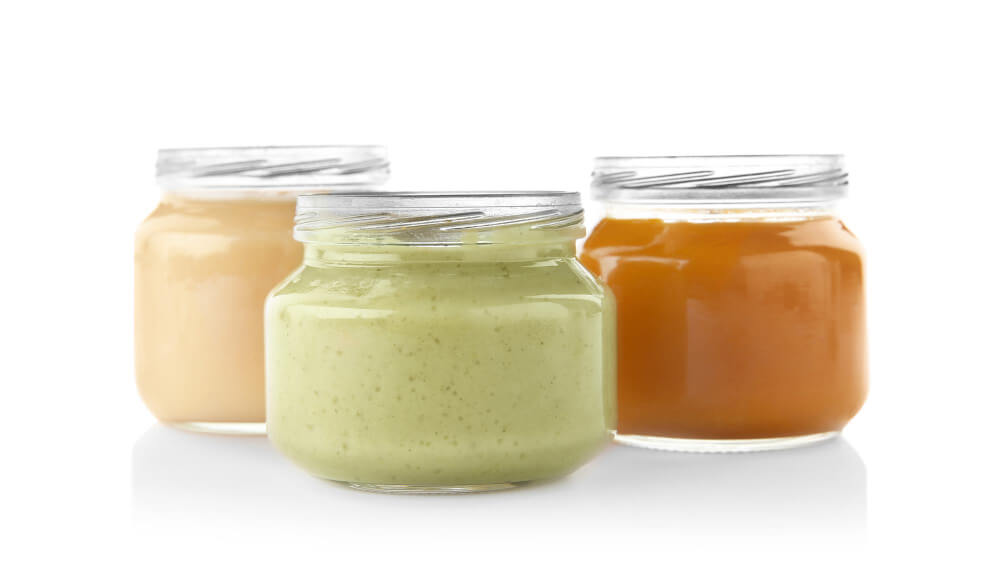 Three glass jars filled with different taco sauces: creamy orange, vibrant green, and deep orange, arranged against a white background.