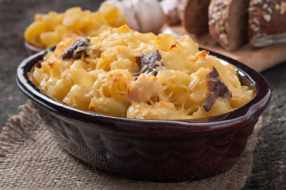 A bowl of macaroni and cheese with a crispy, golden cheese topping and small pieces of beef.