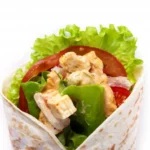 Close-up of a Chicken Caesar Wrap filled with fresh lettuce, juicy tomatoes, grilled chicken, and creamy Caesar dressing.