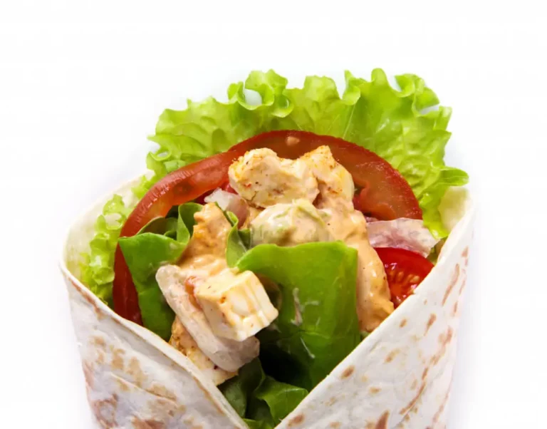 Close-up of a Chicken Caesar Wrap filled with fresh lettuce, juicy tomatoes, grilled chicken, and creamy Caesar dressing.