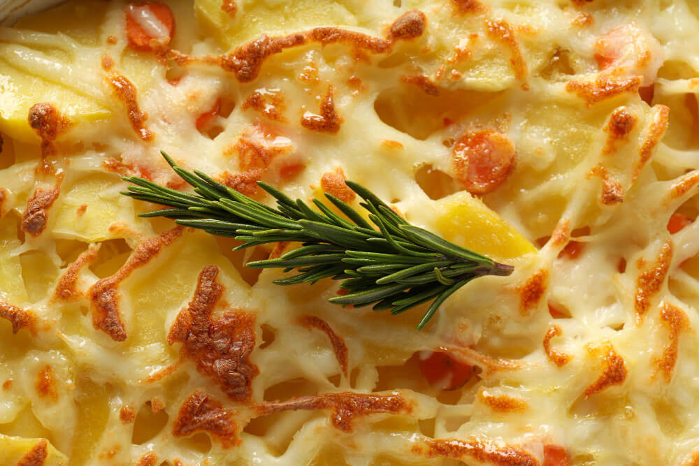 Close-up of cheesy macaroni and cheese with a sprig of rosemary garnish.