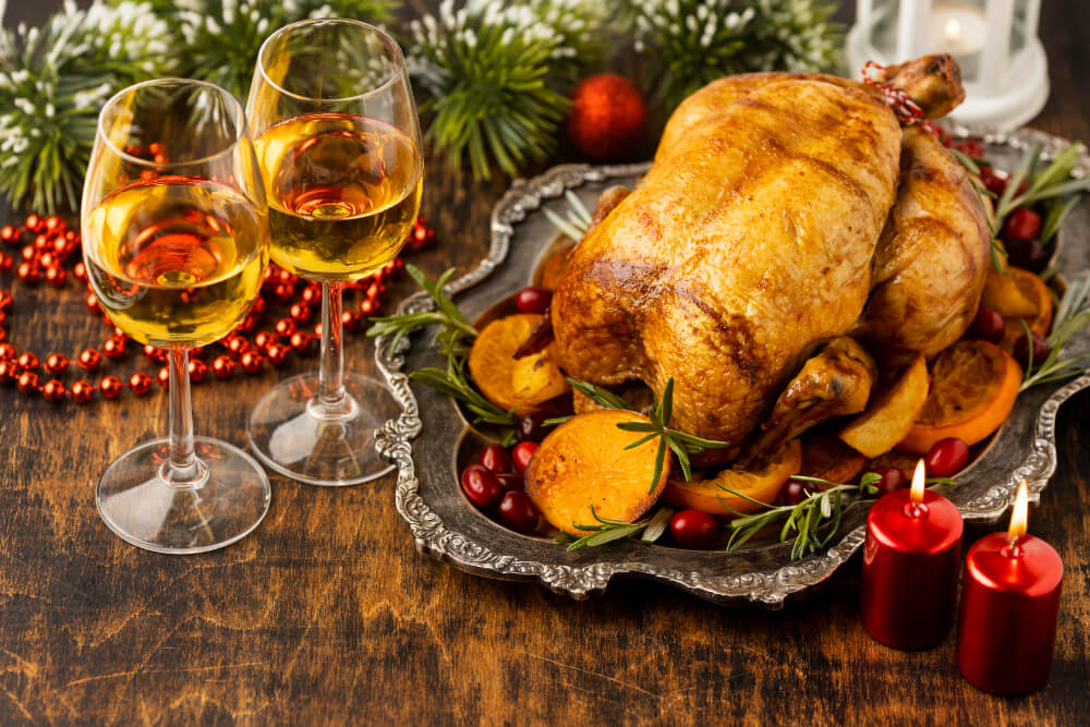 Cooked turkey served on a festive platter with garnishes and wine glasses.