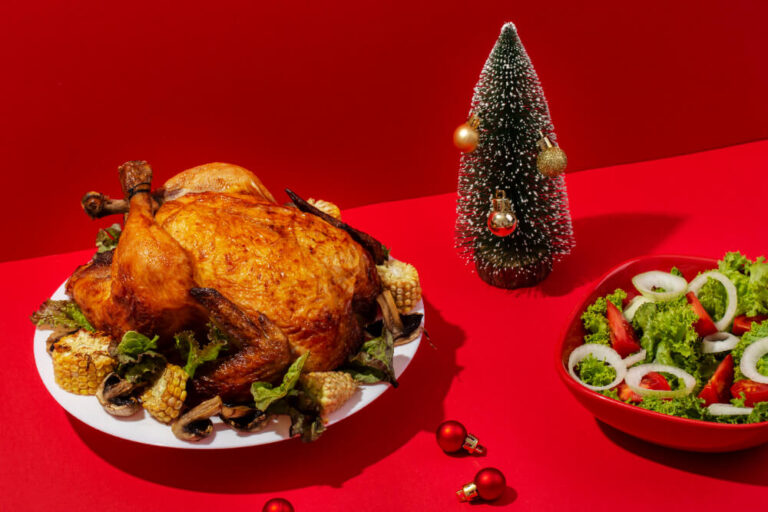 A roasted turkey served on a festive table with corn, mushrooms, and greens, accompanied by a fresh salad and Christmas decorations.