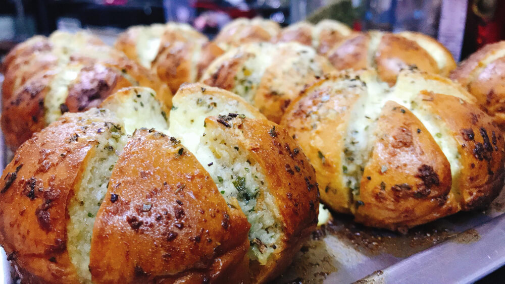 Freshly baked pull apart garlic bread rolls filled with herb butter, arranged on a baking tray.