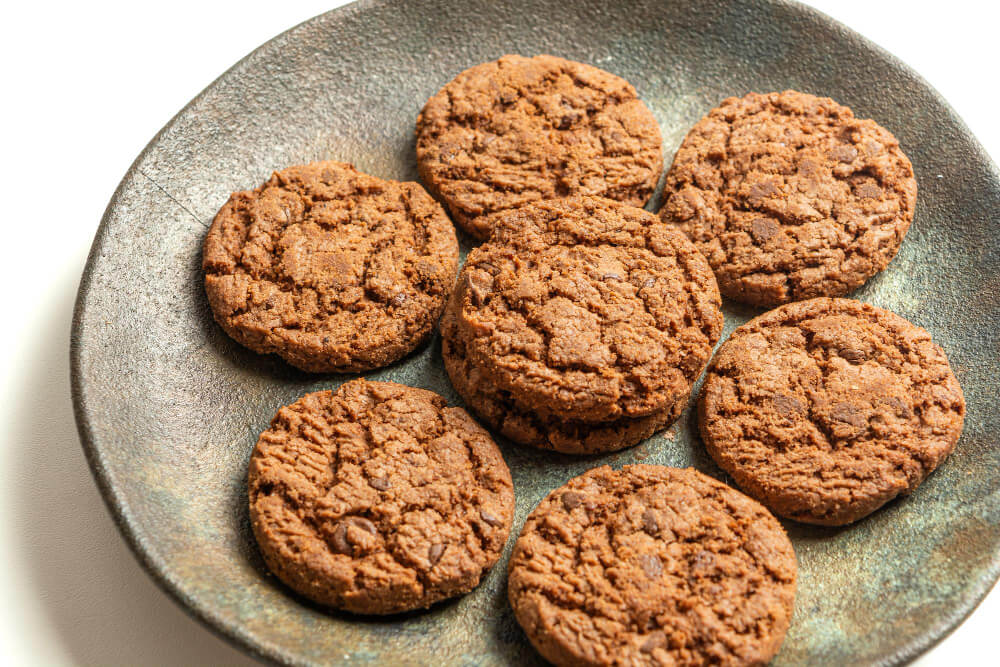 Freshly baked chocolate chip cookies arranged on a rustic green plate.