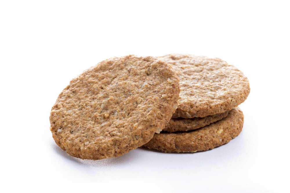 Fresh oatmeal cookies stacked with one leaning in the front, isolated on a clean white background.