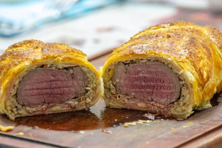 Sliced Individual Beef Wellington showing medium-rare beef wrapped in flaky puff pastry with mushroom duxelles.