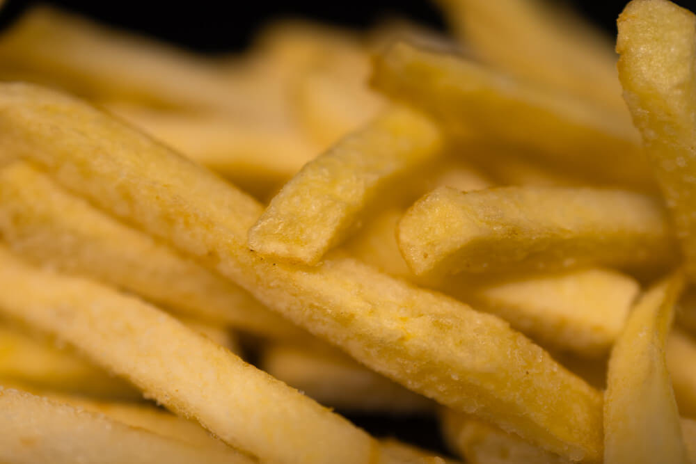 A close-up of golden, crispy French fries with a light, salted coating, cooked to perfection.