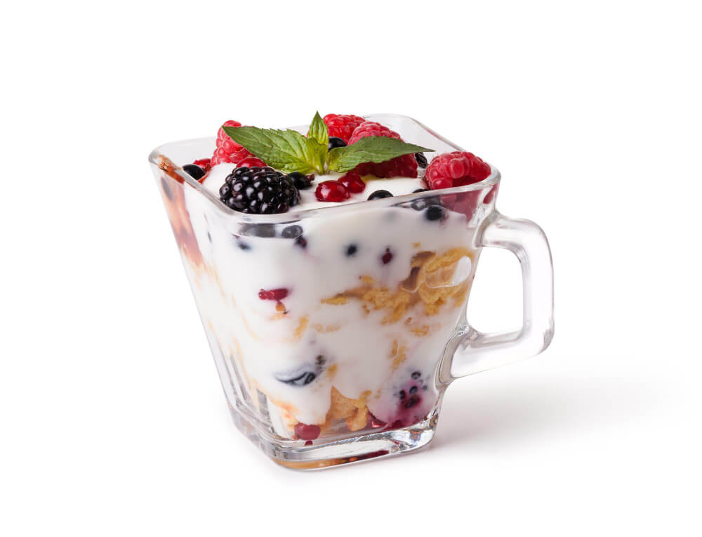 A delicious yogurt parfait with layers of yogurt, granola, and mixed berries in a clear glass cup, garnished with a mint leaf.