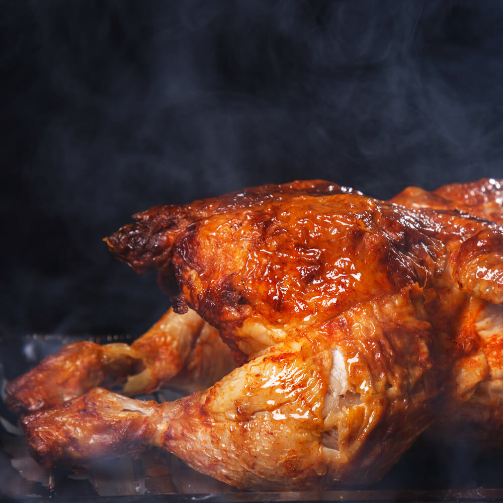 Close-up of a golden-brown roasted turkey with a smoky background.