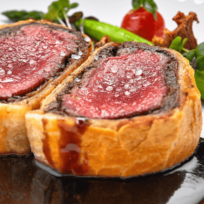 Close-up of sliced Individual Beef Wellington with a medium-rare beef center, mushroom duxelles, and golden puff pastry.